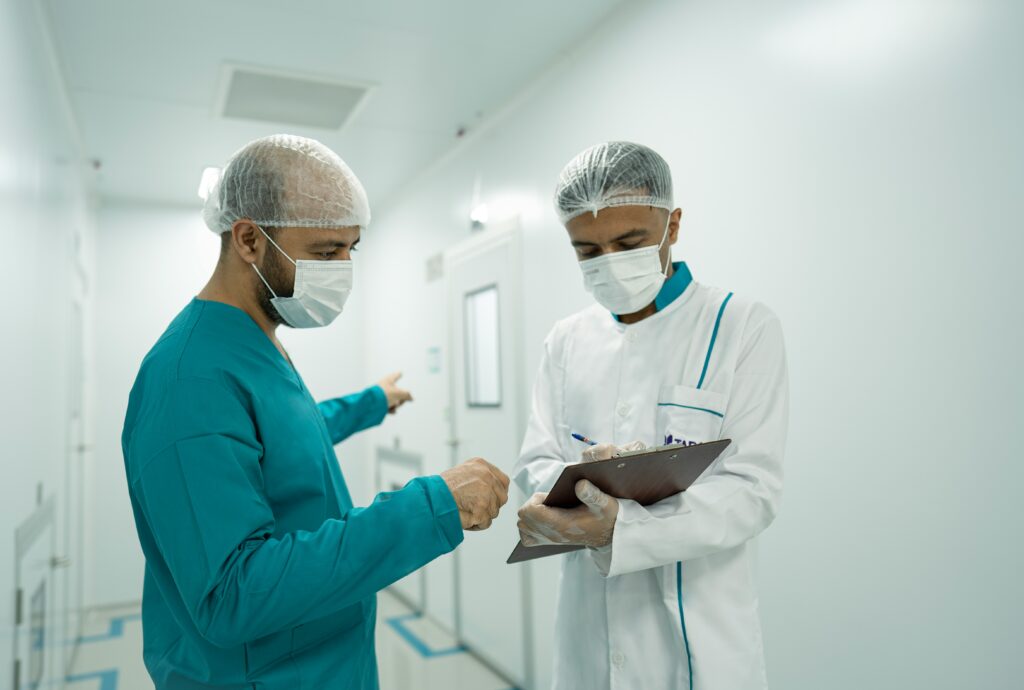 A specialist and surgeon discuss the details of a patient's referral over a clipboard.